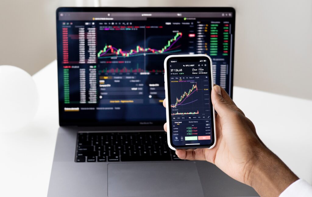 De Principiante a Experto: Los Mejores Libros de Day Trading; un hombre haciendo 'day trading' en su celular y computadora.